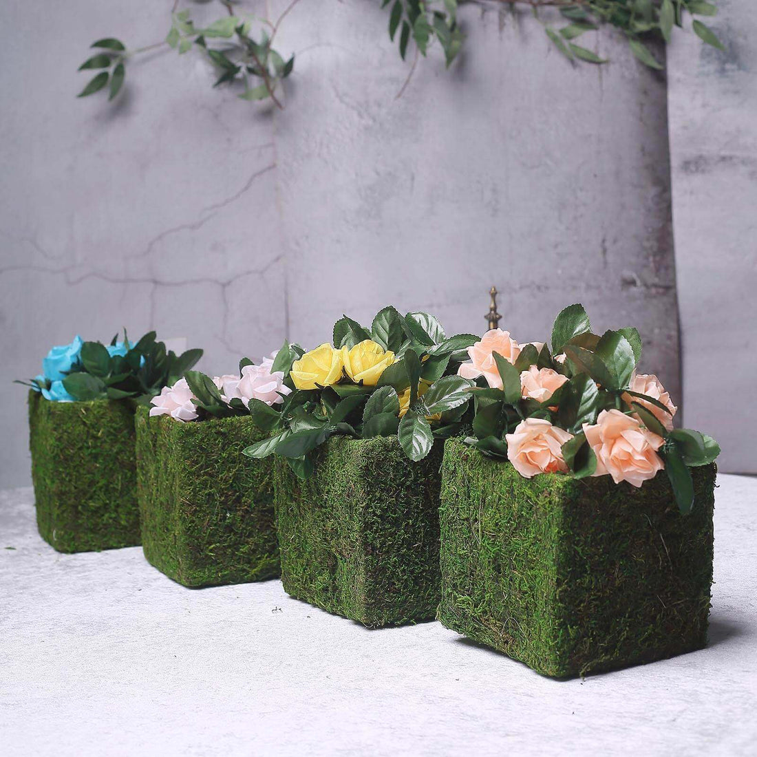 Artificial flower arrangements in moss-covered boxes.